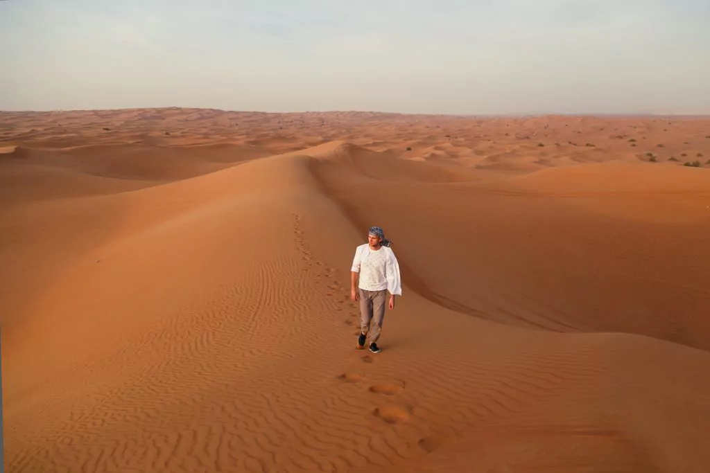 Mann spaziert durch die Wüste in Dubai
