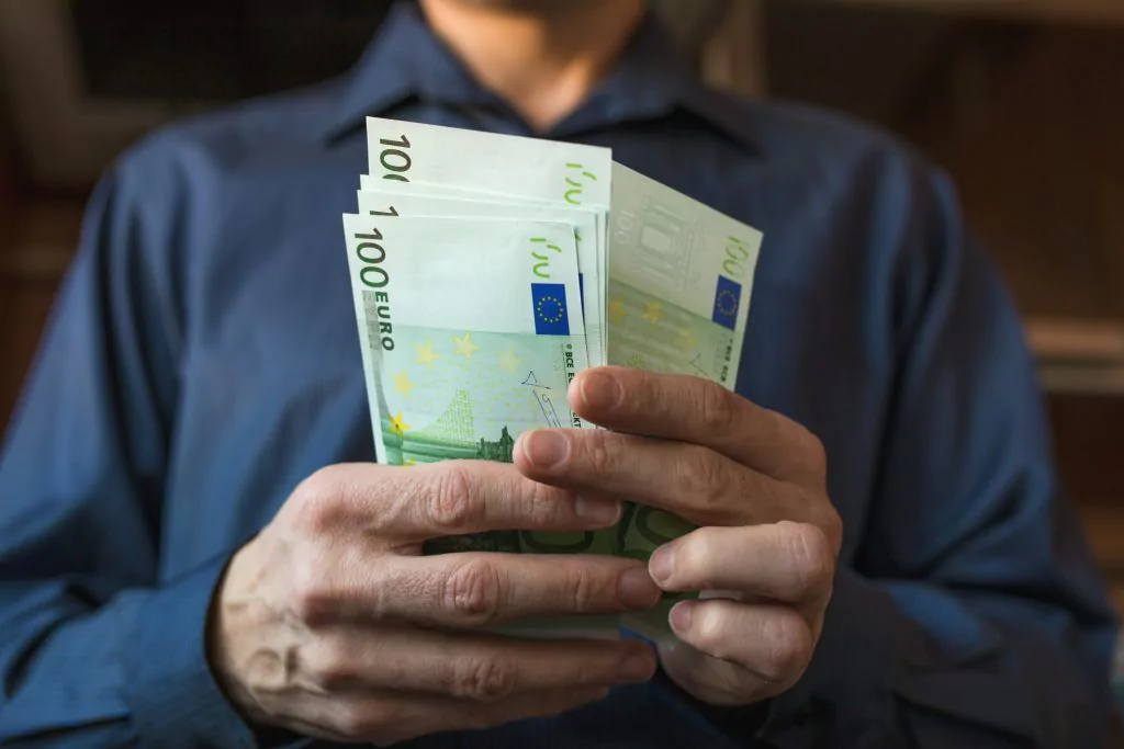 Mann der 100-Euro-Geldscheine in der Hand hält