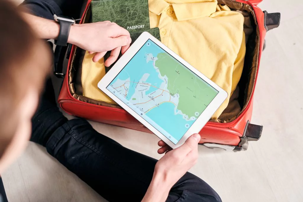 Tablet mit geöffneter Landkarte auf einem gepackten Reisekoffer