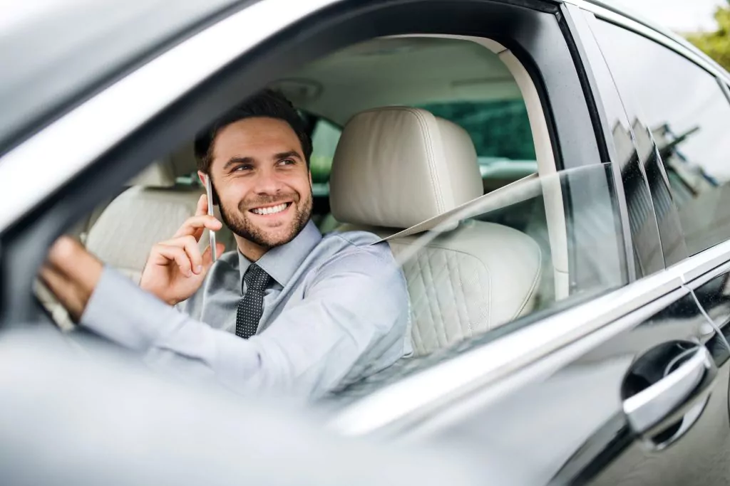 Mann mit Handy am Ohr lacht aus einem Auto