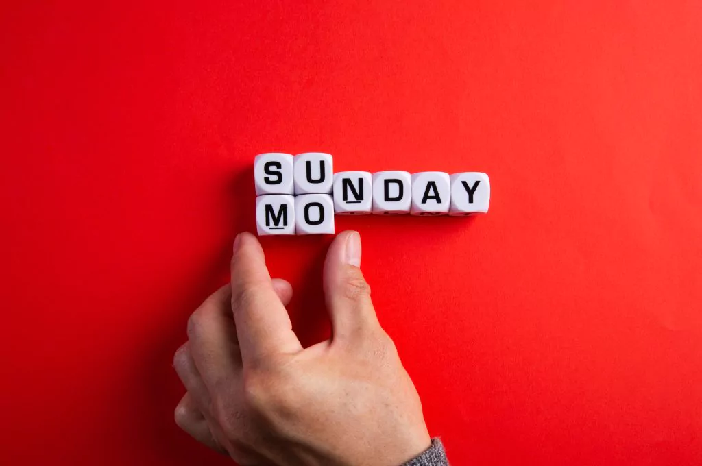Hand zeigt auf ein Wortspiel aus "Sunday" und "Monday"