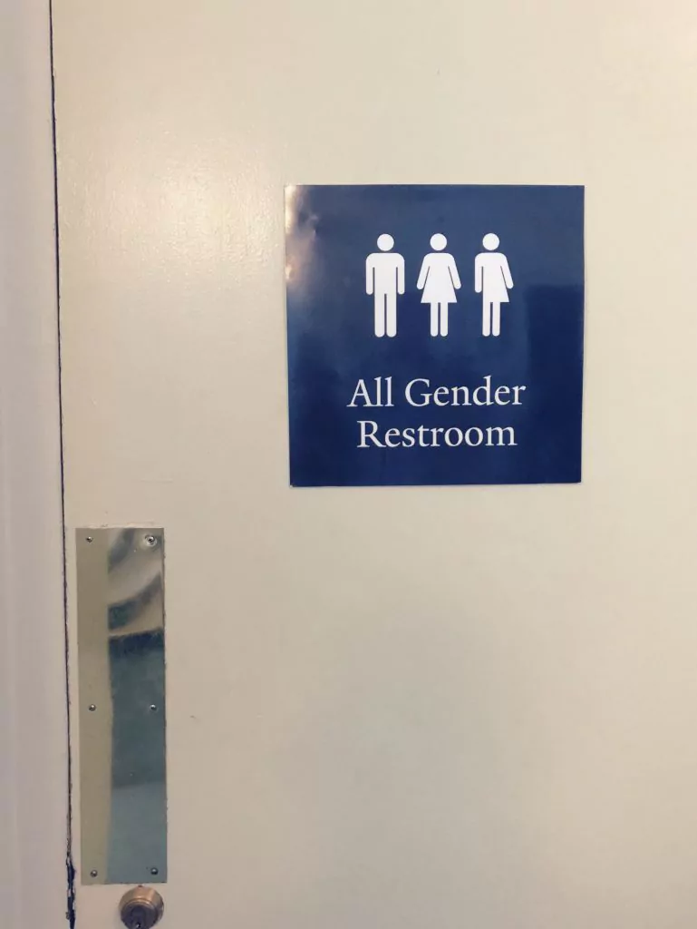 Blaues Schild mit drei Figuren auf dem "All Gender Restroom" steht