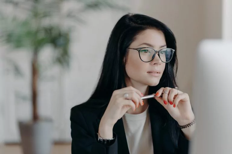 Frau mit Brille hält Stift in der Hand