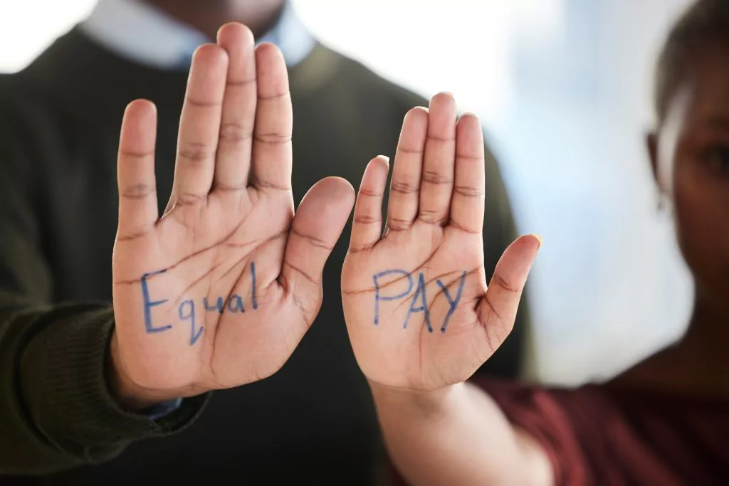 Männerhand mit dem Wort Equal und Frauenhand mit dem Word Pay