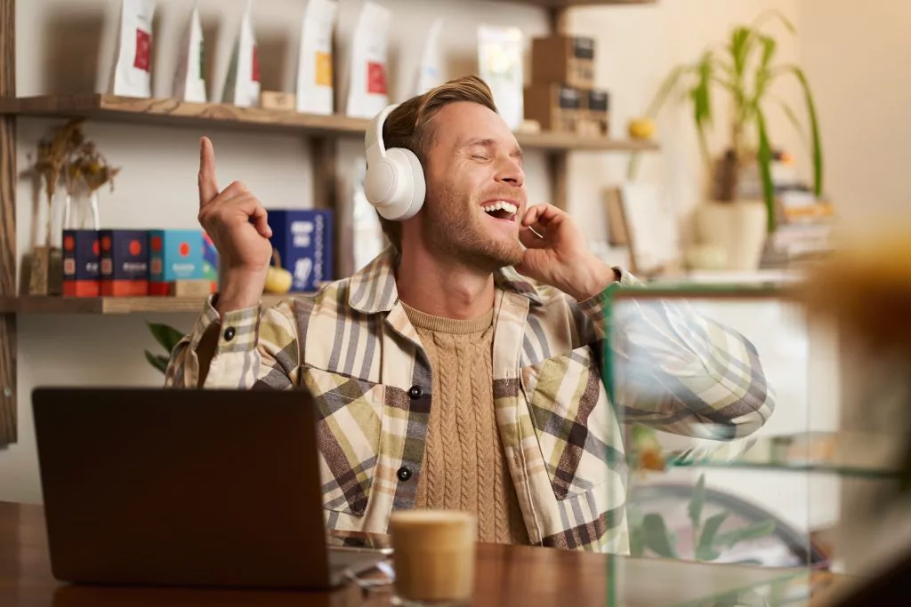 Mann hört Musik über Kopfhörer und sitzt an seinem Arbeitsplatz
